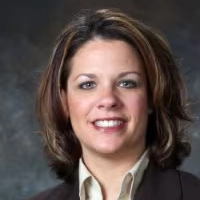 Smiling woman with brown hair wearing a dark blazer