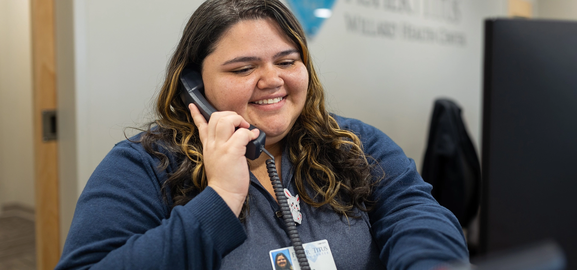 receptionist on the phone talking to a patient with a smile