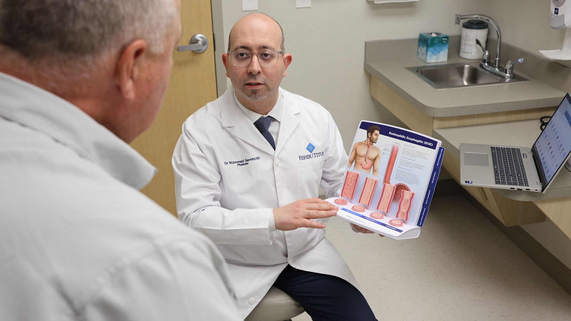 Muhammad Talal Sarmini, MD, shows a patient a diagram of the digestive tract to a patient.